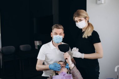 gülümseyen doktor ve Yardımcısı çapraz elle diş kliniği kamera bakıyor