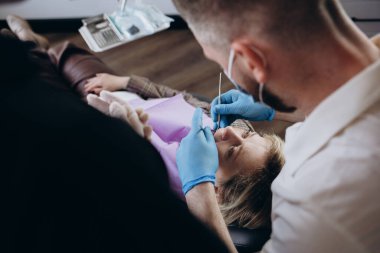 Dişçi muayenesinde gülümseyen bir kadın. Diş hekimleri hastanede bir kadın hastayı tedavi ediyor..