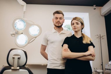 Kamera ayakta modern diş kliniği içinde işyerinde bakarak iki gülümseyen Doktor portresi