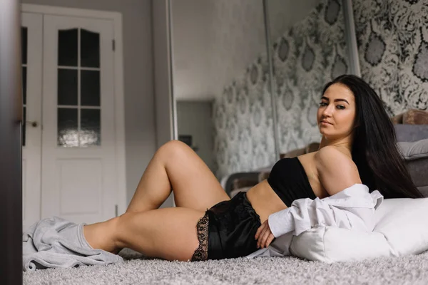 一个穿着性感丝绸睡衣的女孩坐在床边的地板上 — 图库照片