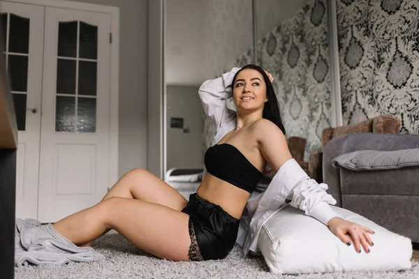 Büyük beden bir kadın sabah yatak odasındaki yatakta oturuyor olacak. Kızın koyu saçları ve güzel göğüsleri var. Gömlekli ve beyaz iç çamaşırlı güzel şişman kız. Beyaz çarşaflı büyük bir yatak..