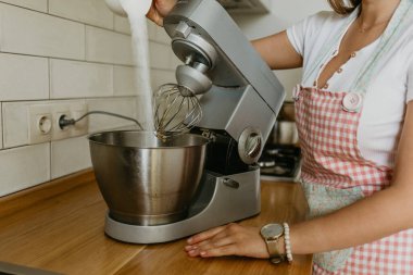 Genç bir kadın mutfakta yemek pişiriyor.