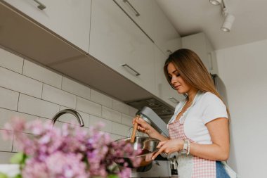 Mutfakta balık pişirirken genç ve mutlu bir bayanın görüntüsü. Kameraya bakıyorum..