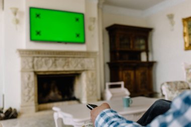 Boş Yeşil perde Tv uzaktan kumanda tutan ufuk kadın el ile.