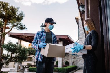 Koruyucu maskeli ve tıbbi eldivenli kurye paket yemek getiriyor. Karantina, hastalık salgını, koronavirüs covid-19 salgını altında teslimat hizmeti.