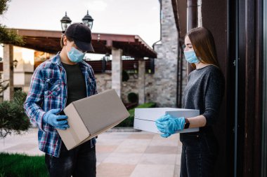 Koruyucu maskeli ve tıbbi eldivenli kurye paket yemek getiriyor. Karantina, hastalık salgını, koronavirüs covid-19 salgını altında teslimat hizmeti.