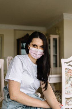 Coronavirus konsepti. Maskeli kadın evden çalışıyor. Ev karantinasında koruyucu maske takan bir iş kadını. Evden çalışıyorum. Ellerini dezenfektan jeliyle temizliyor.