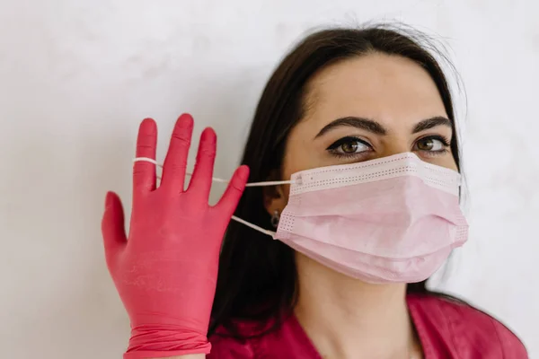 portrait of a doctor putting on a mask and pink uniform. isolated on white background