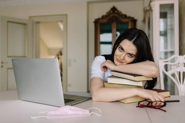 Pretty student with laptop and books quarantining from home