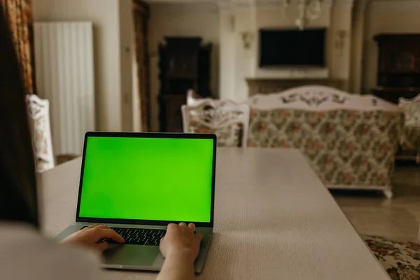 Woman using laptop with green screen. Woman\'s hands typing on a laptop keyboard. Business, communication, freelance and internet concept