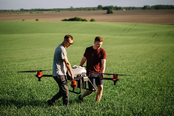 Tarlada çim filizinin yanında yürüyen dronlu çiftçi.