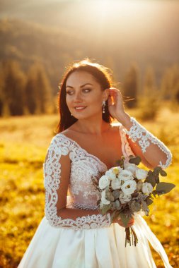 Mutlu, güzel, genç gelin gün batımında bir çayırda.