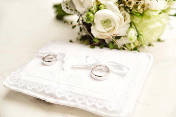 Almofada branca com anéis de casamento — Fotografia de Stock