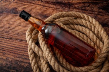 Kırsal Amerika 'da alkolizm ve aşırı damıtılmış alkol ve sert içki içme konsepti konsepti bir şişe viski, brendi ve ip kementle ahşap zemin üzerinde