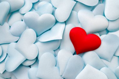One single red textile heart on multiple pastel blue hearts with copy space concept for bond between lovers, romantic relationship and romance backgrounds
