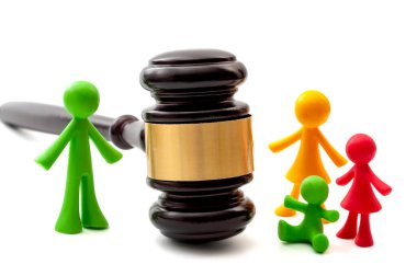 Miniature figurines representing father, mother and children separated by judge gavel concept for family law ruling, joint parental child custody, verdict in legal court and painful divorce dispute