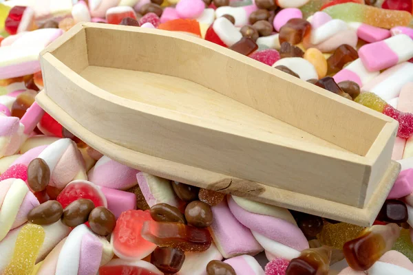 Wood coffin on top of pile of assorted sweets, junk food and candy concept for death caused by diabetes and metabolic disease, obesity due to an unhealthy diet and hazardous blood sugar levels