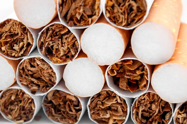 Full frame image of close up on a stack of many cigarettes piled up concept for health issues due to cigarette smoking, dangerous lifestyle backgrounds and tobacco addiction causes lung illness