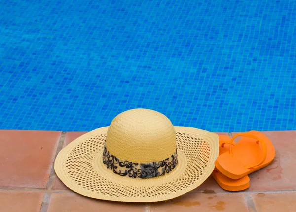 Sombrero de paja y sandalias al lado de la piscina —  Fotos de Stock