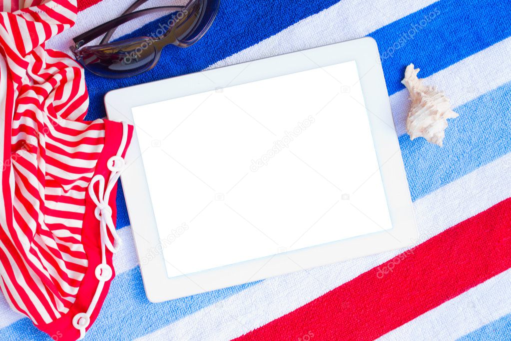 Tablet on beach towels with sunbathing accessories