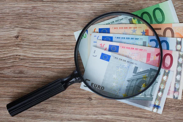 Euro banknotes under magnifying glass — Stock Photo, Image