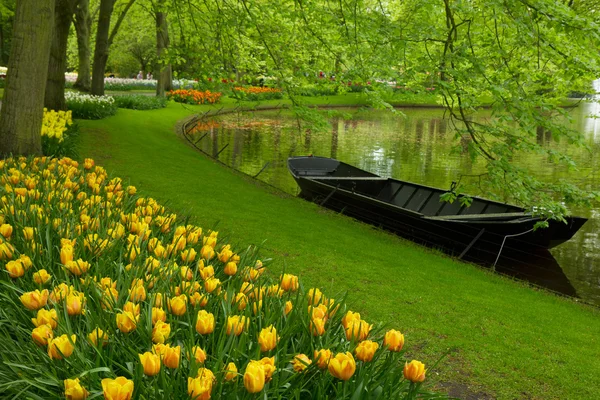 Весенний сад с каналом и лодкой — стоковое фото