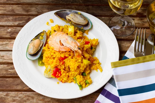 Paella sloužil v bílé desky na dřevěný stůl — Stock fotografie