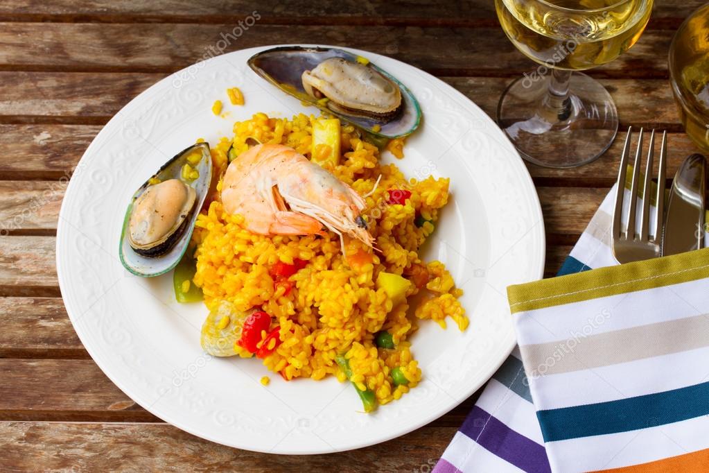 Paella served in white plate on wooden table