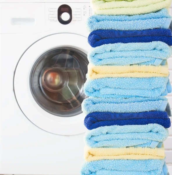Куча чистых полотенец со стиральной машиной — стоковое фото