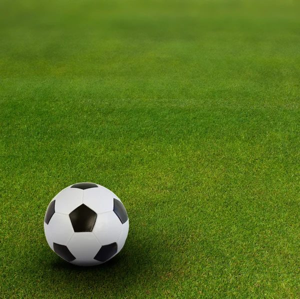 Pelota de fútbol en el campo de fútbol verde — Foto de Stock