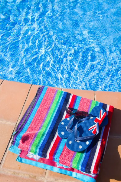 Toalha e sandálias perto da piscina — Fotografia de Stock