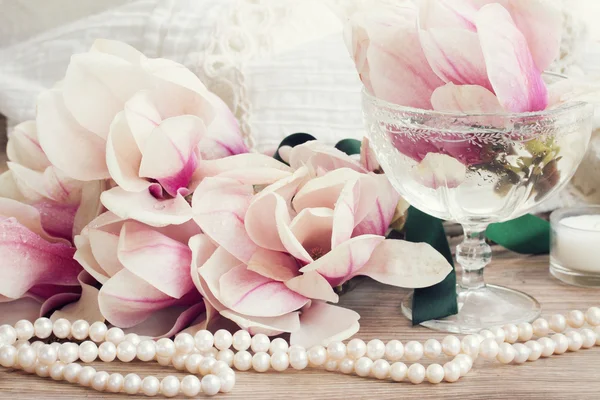 Magnolia flowers with pearls on wooden table — Stock Photo, Image