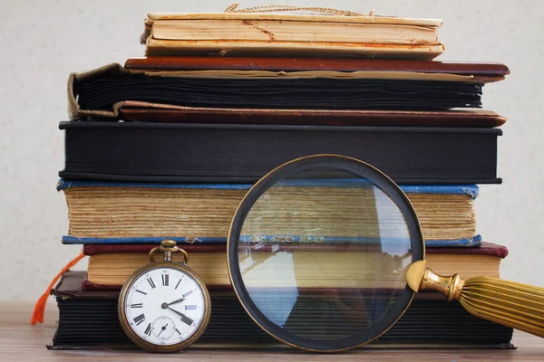 Reloj antiguo con lupa sobre fondo de libros —  Fotos de Stock