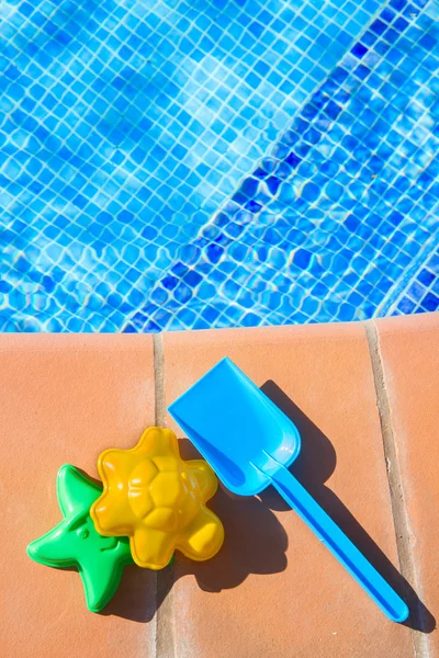 Juguetes de playa de plástico cerca de la piscina — Foto de Stock