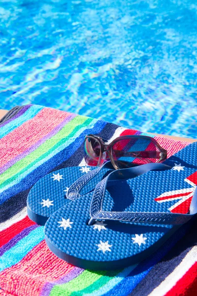 Toalla y sandalias cerca de la piscina — Foto de Stock