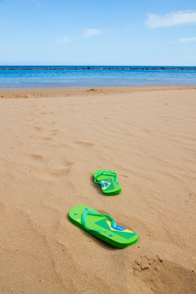 Zelené sandály na písečné pláži — Stock fotografie