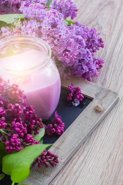 Fresh lilac flowers with candle — Stock Photo, Image