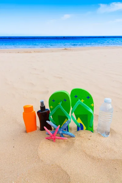 Sandalet ve kum plajındaki su şişe — Stok fotoğraf