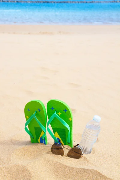 Kumlu sahilde yeşil sandalet — Stok fotoğraf