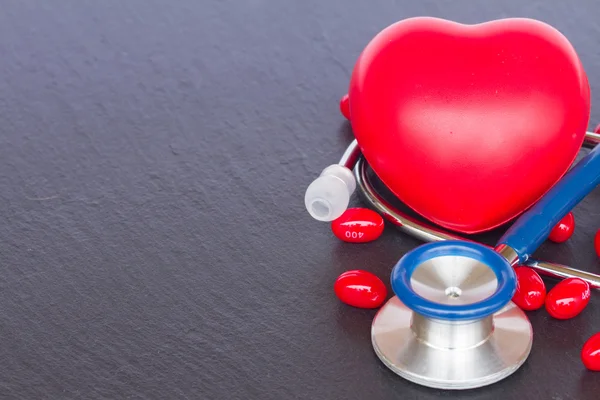 Estetoscópio com dois corações vermelhos e comprimidos — Fotografia de Stock