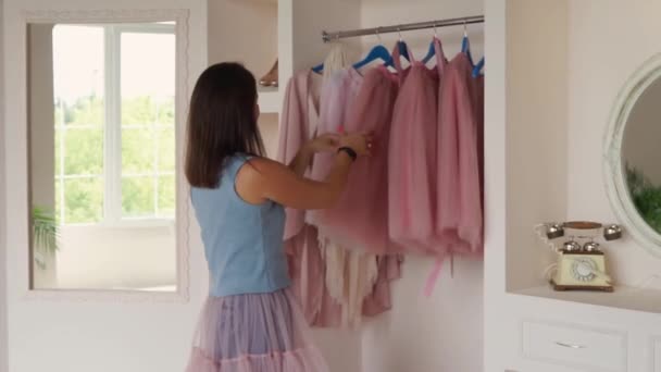 Brunette vrouw staan bij garderobe in de kamer en kiezen glamoureuze avondjurk — Stockvideo