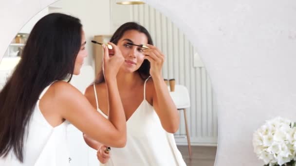 Brunette vrouw met lange rechte donker haar en schone huid doen make-up routine — Stockvideo