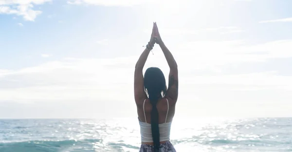 Mulher em roupas esportivas praticando ioga e meditando na praia de manhã — Fotografia de Stock