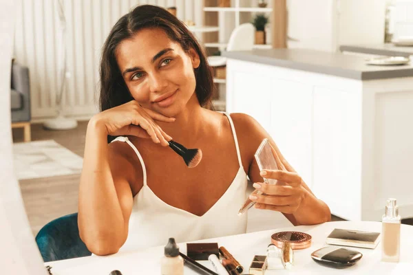Morena mujer con el pelo largo y oscuro y la piel limpia haciendo la rutina de maquillaje —  Fotos de Stock
