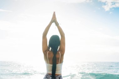 Spor elbiseli kadın sabahları yoga yapıyor ve plajda meditasyon yapıyor.