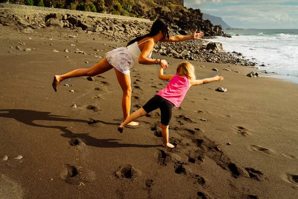 Healthy happy family mom and daughter doing stretching exercises on seaside — Stock Photo, Image