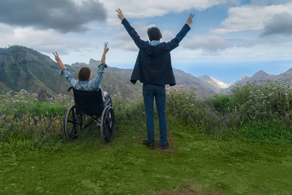 Jeune homme et sa femme en fauteuil roulant voyageant ensemble en voiture dans les montagnes — Photo