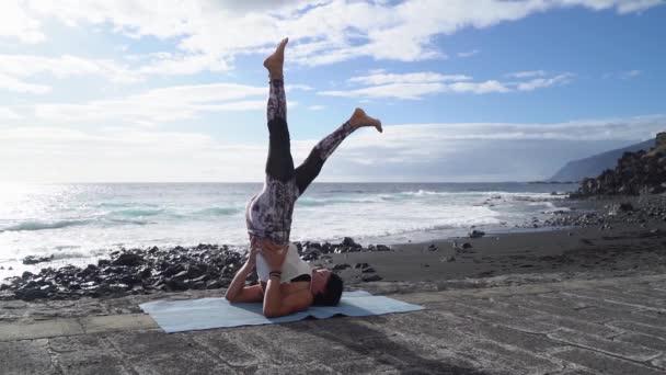 Mulher em roupas esportivas praticando ioga e meditando na praia de manhã — Vídeo de Stock