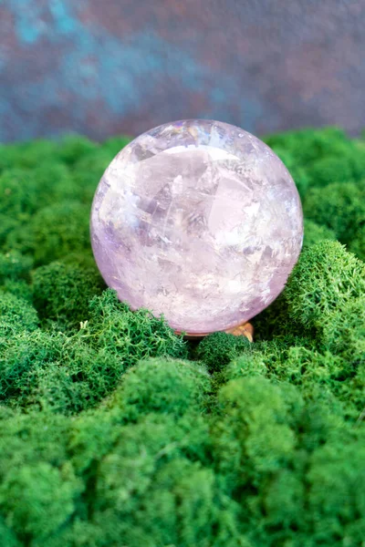 Crystal ball of aametist stone on mysterious natural forest background. Magic healing Rock for Crystal Ritual, Witchcraft, spiritual esoteric practice