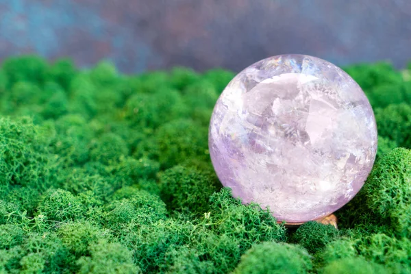 Crystal ball of aametist stone on mysterious natural forest background. Magic healing Rock for Crystal Ritual, Witchcraft, spiritual esoteric practice